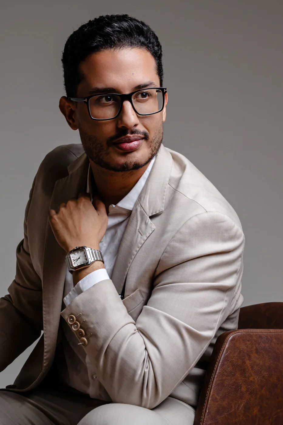 Dr. Erick Neres sentado, de terno bege, no estúdio